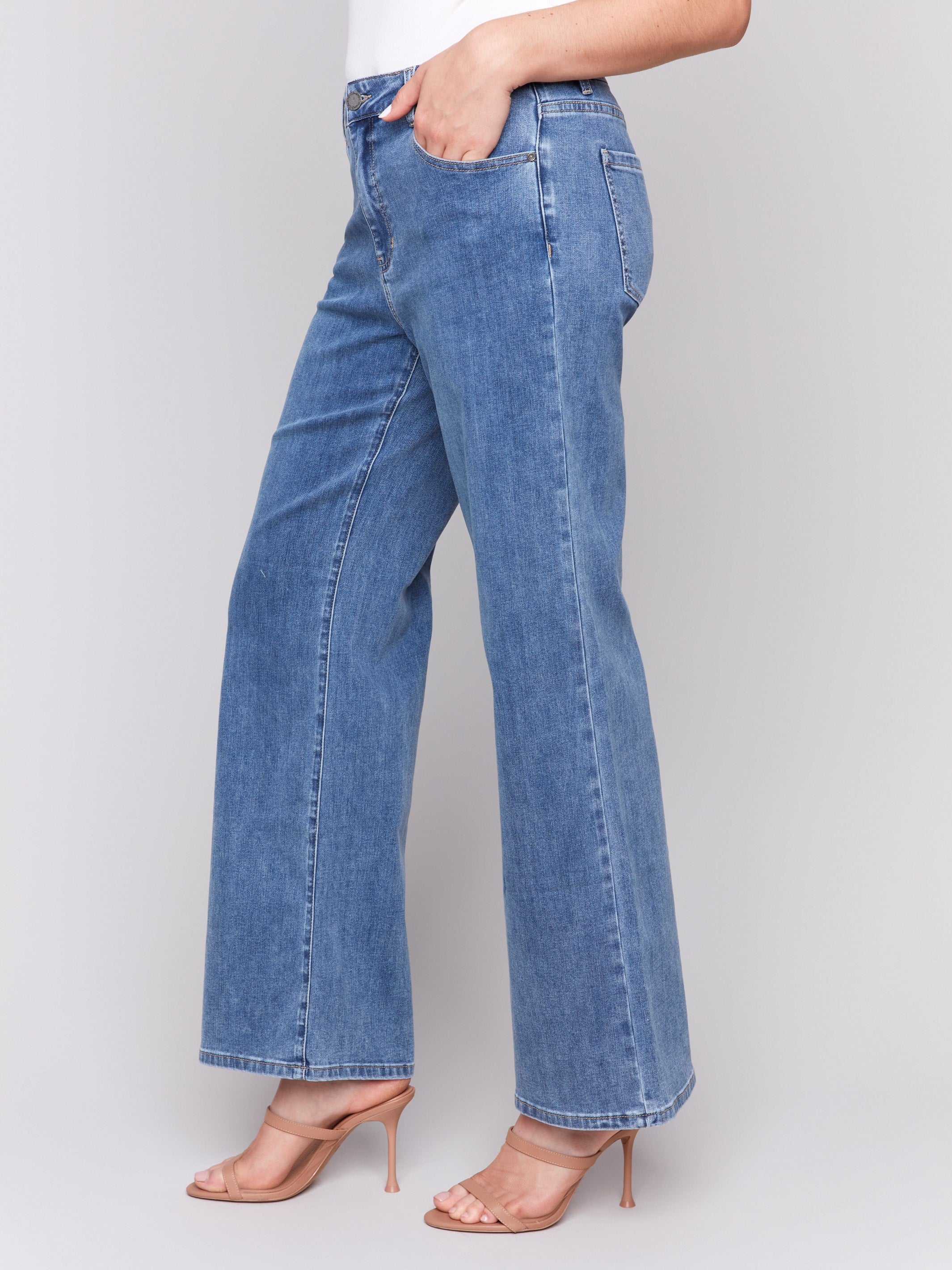 Medium blue wide-leg jeans with five-pocket design featuring a button closure and relaxed fit by Charlie B.