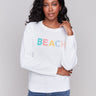 White cotton knit sweater with round neckline and vibrant design by Charlie B.