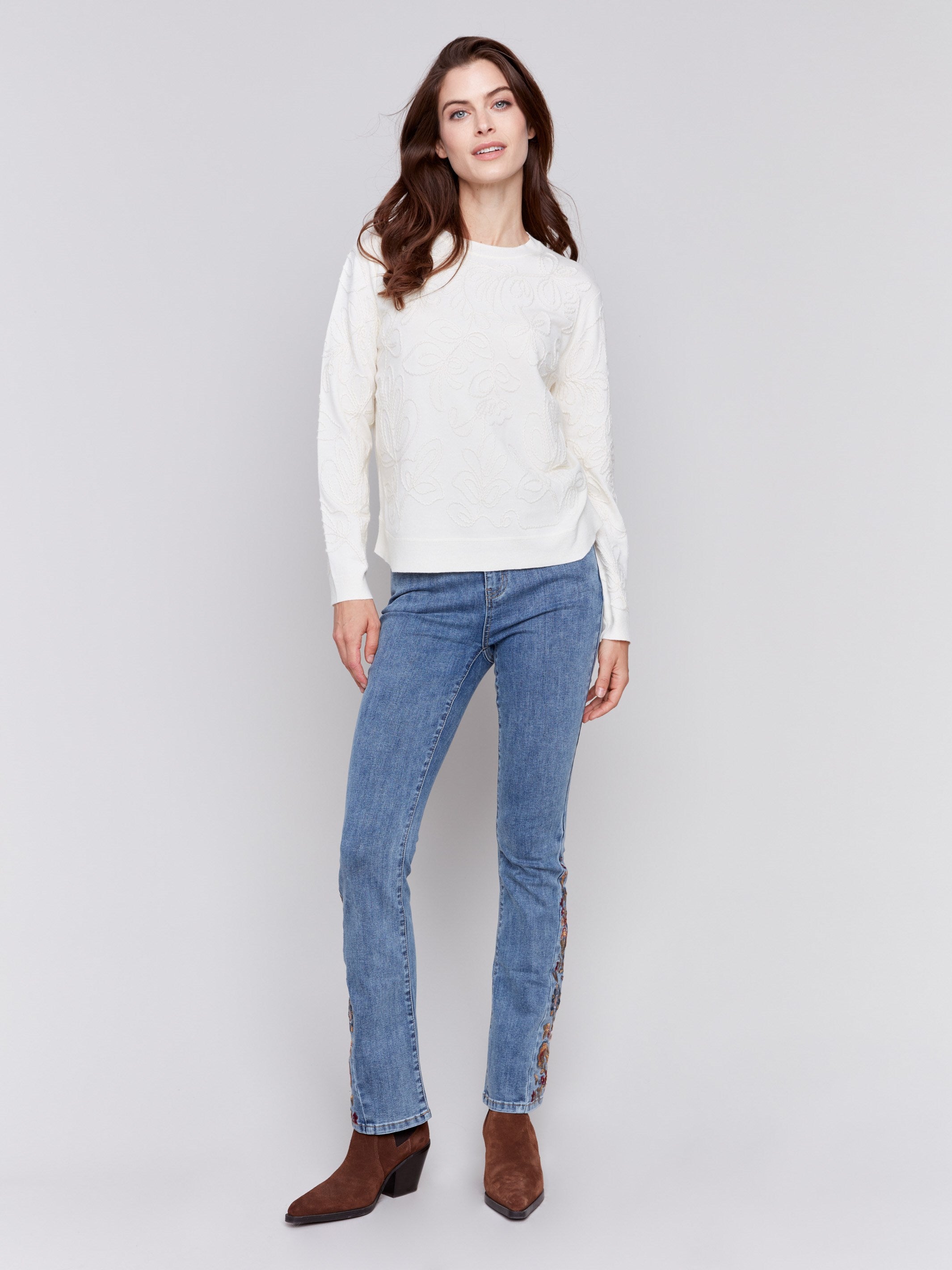 White sweater with floral embroidery, long sleeves, and a round neckline by Charlie B.