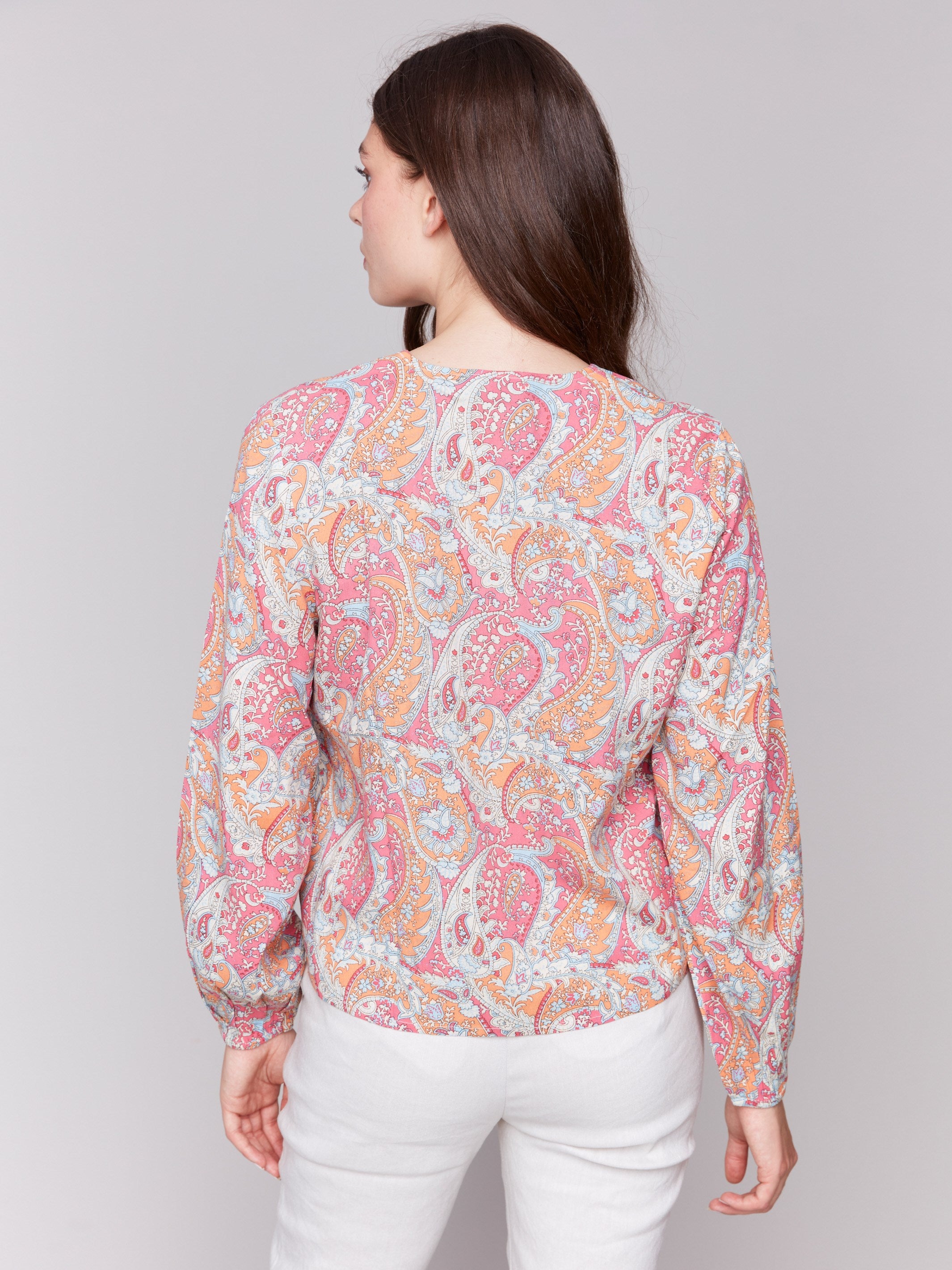 Front tie knot detail on a colorful paisley long-sleeve blouse, perfect for any occasion by Charlie B.