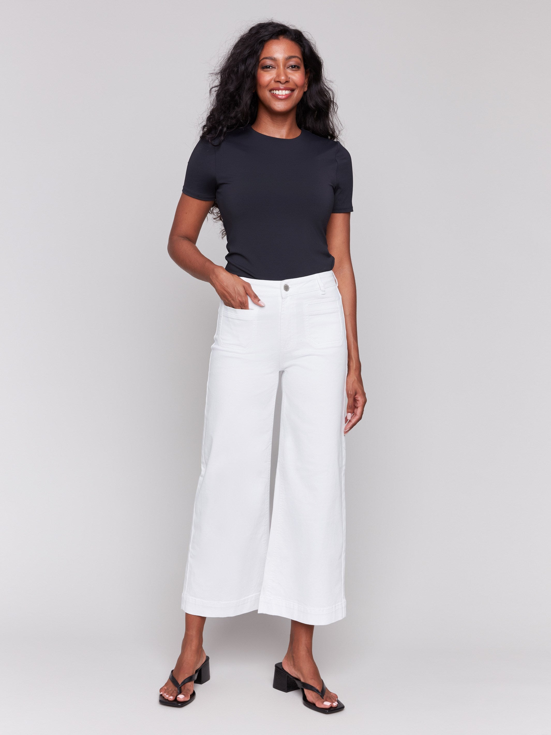 White flare twill pants featuring front patch pockets with a regular rise, button closure by Charlie B.