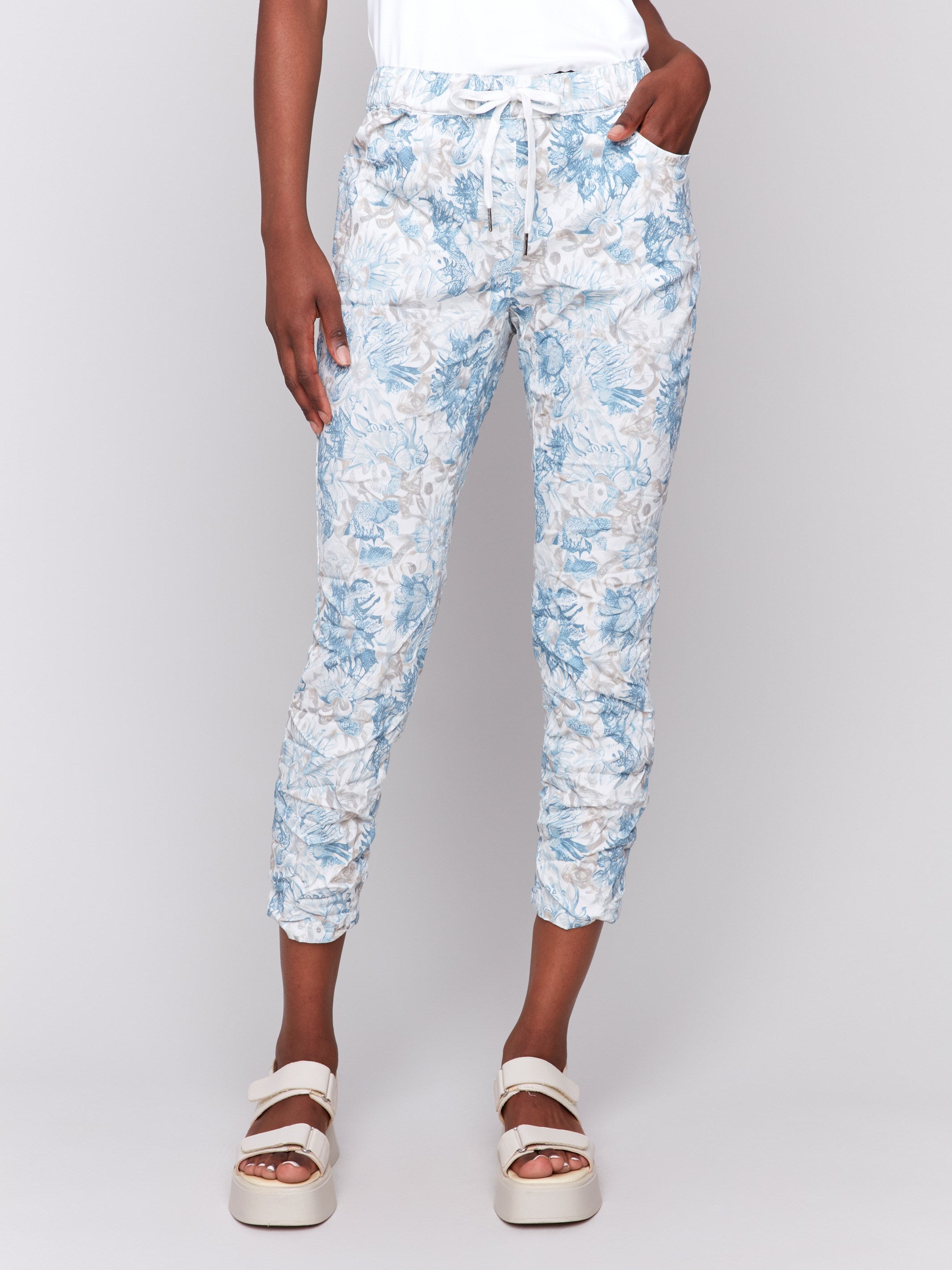 Cropped length jogger pants featuring a blue and white floral print by Charlie B.