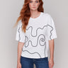 White t-shirt with drop shoulder design, showcasing black soutache detailing by Charlie B.