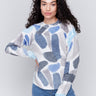 Woman wearing a reversible sweater with sapphire blue abstract prints and a crew neckline by Charlie B.