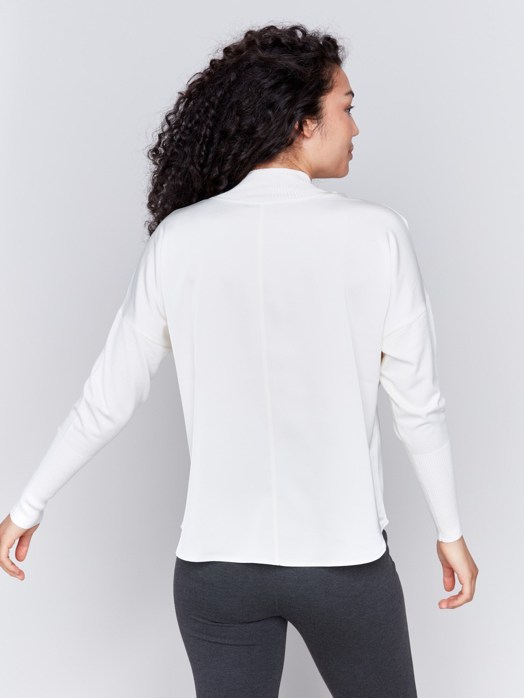 Ecru white satin-knit top with a mock neck and front seam detail, featuring long sleeves and ribbed cuffs by Charlie B.