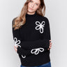 Black mock-neck sweater with white floral embroidery and ribbed texture by Charlie B.