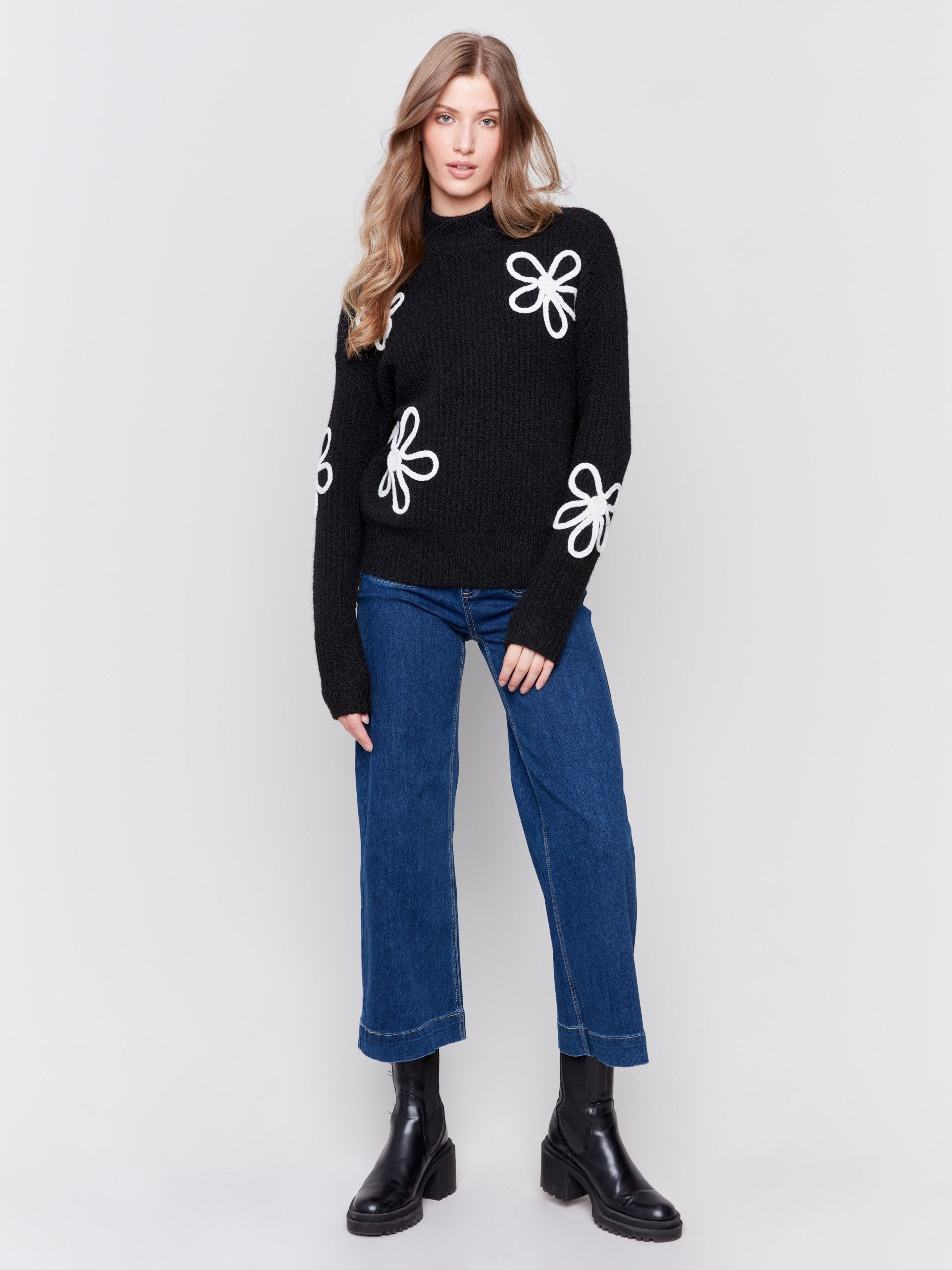 Black mock-neck sweater with white floral embroidery and ribbed texture by Charlie B.