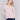 Light pink long-sleeve sweater with front knot detail and V-neckline by Charlie B.