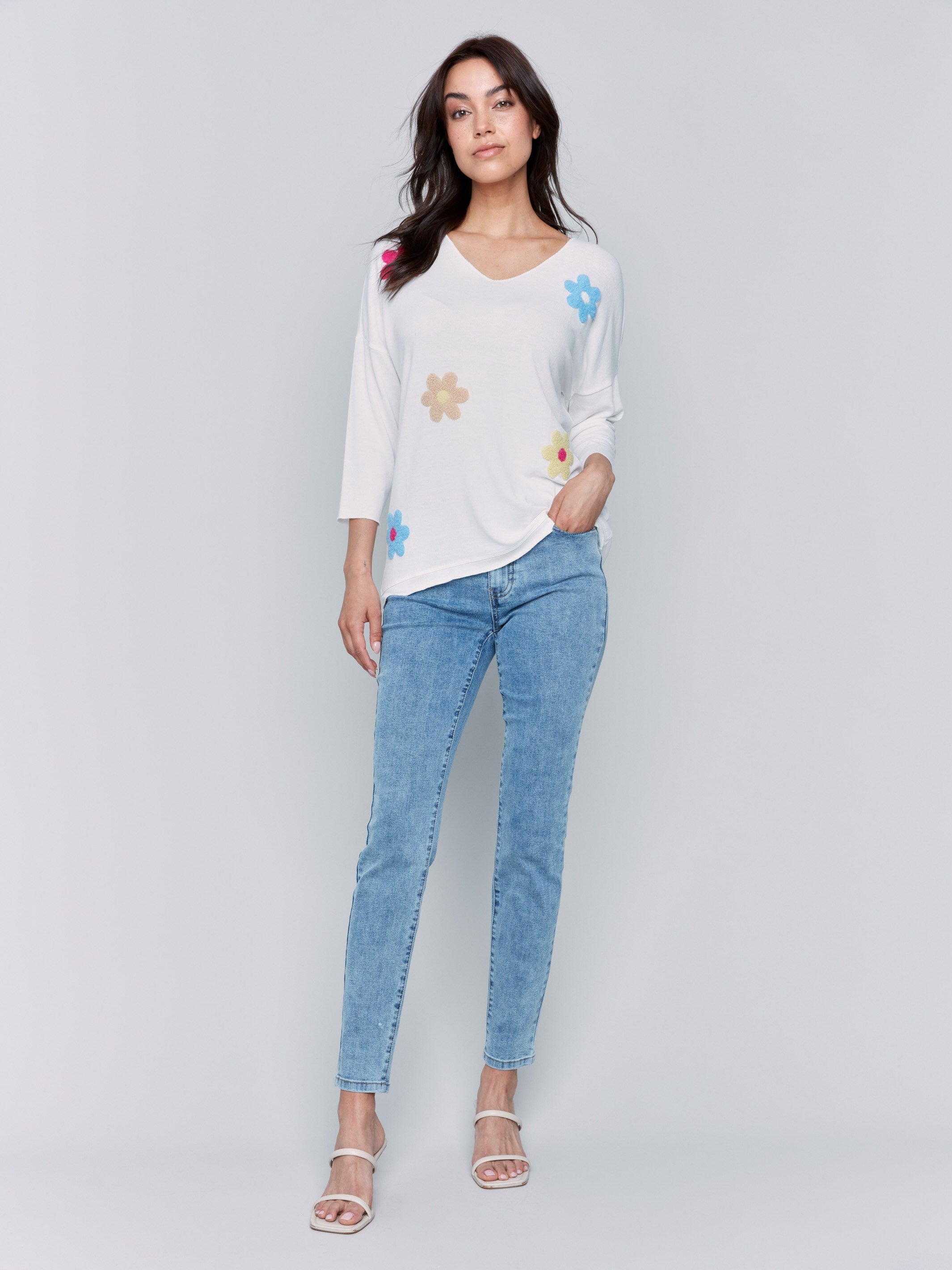 White V-neck knit top with colorful floral appliqués, featuring drop shoulders, by Charlie B.